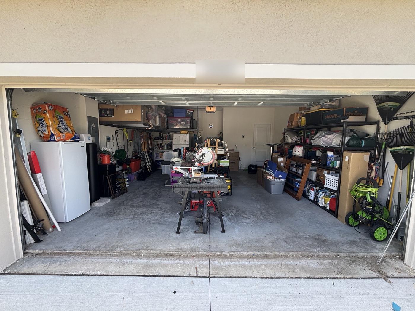 The same garage after: clear floor, tools on shelving, workbench centered, rakes hung on the wall