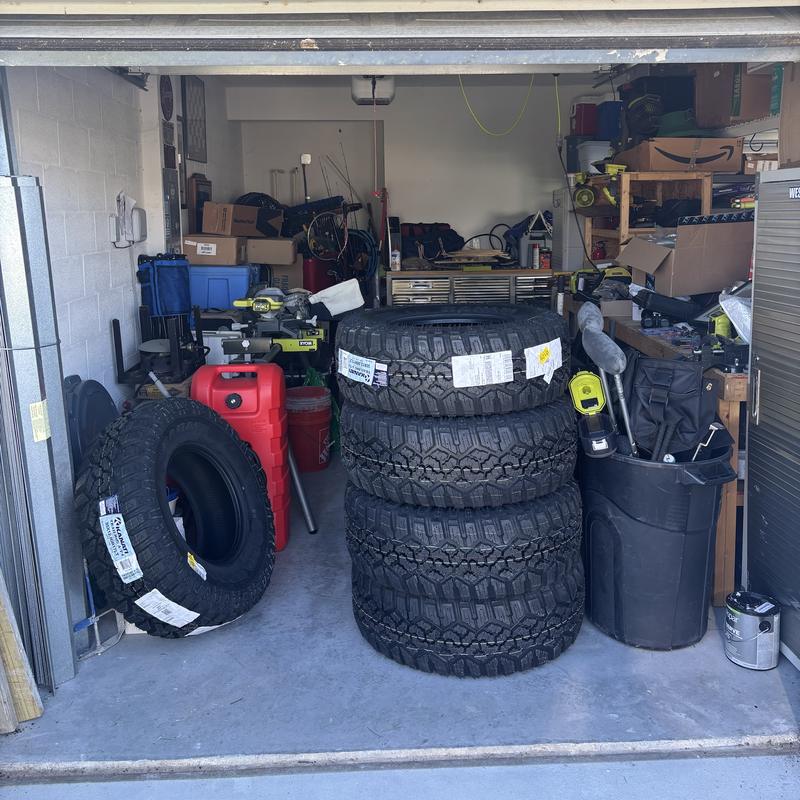 Workshop garage before, blocked by a stack of tires, a gas can, and tools
