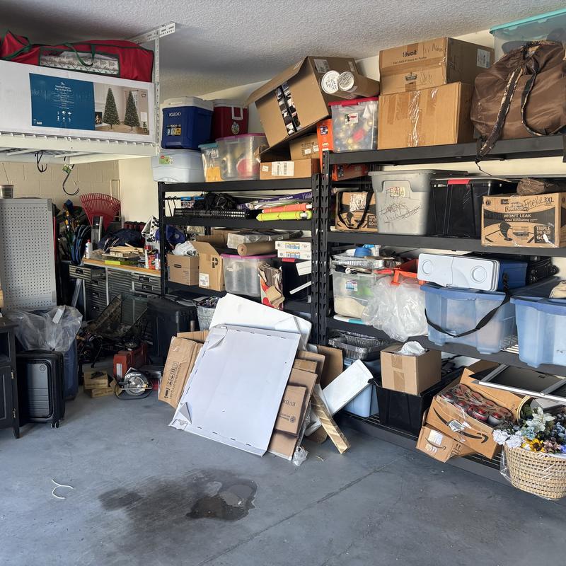 Garage storage wall before, with boxes and loose items spilling off the shelves