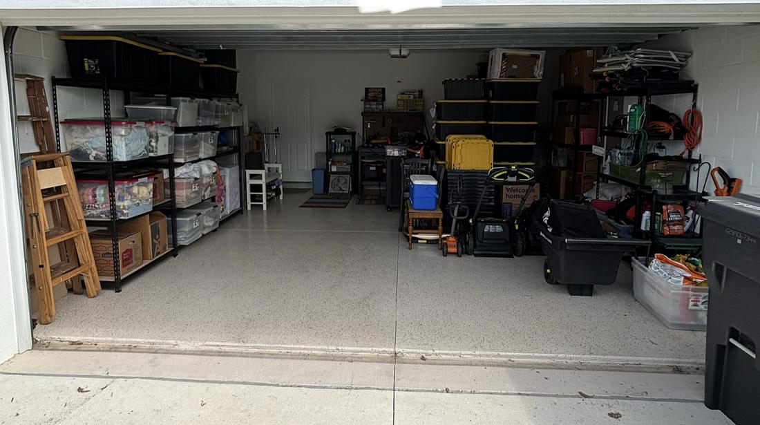 The same two-car garage after, with bins on shelving and the floor clear